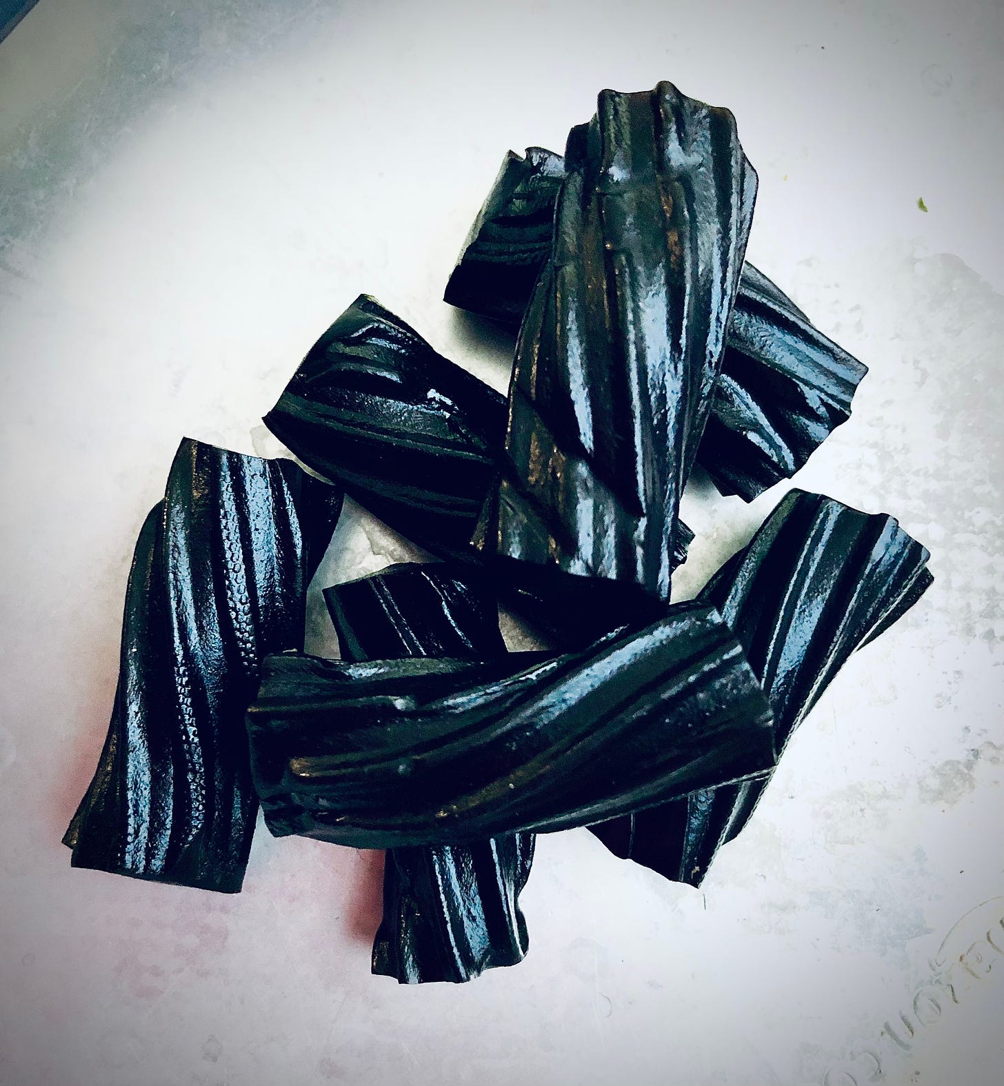 a small pile of black licorice twist candy, shining in the light