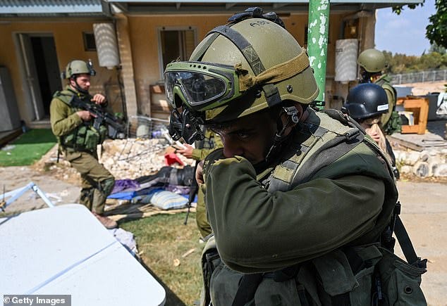 A soldier is overcome with emotion as he searches for bodies in the kibbutz