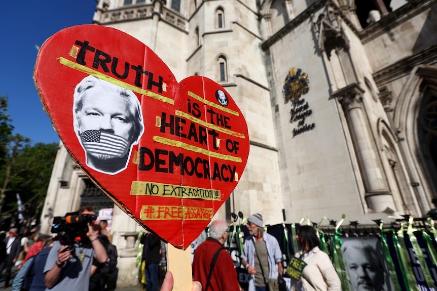A supporter of Julian Assange holds up a sign reading "Truth is the heart of democracy" outside the Royal Court in London.