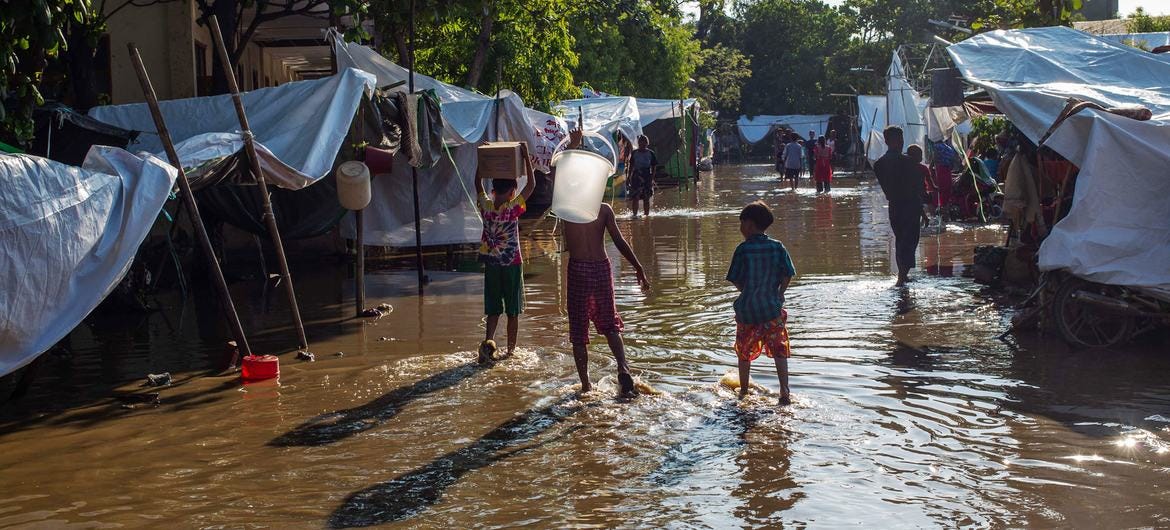 People walk through a flooded township in Myanmar following the early arrival of monsoon rains.