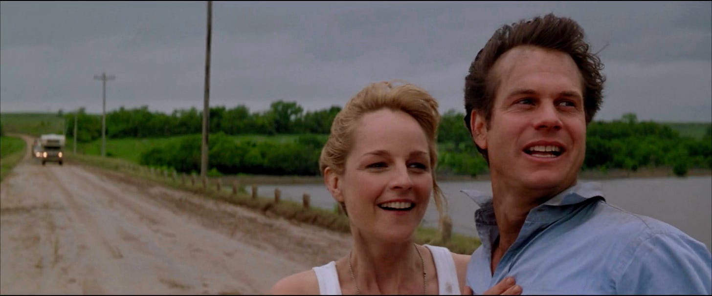 Helen Hunt as Jo (left) and Bill Paxton as Bill (right) in TWISTER. They're holding onto each other after surviving an encounter with a tornado.