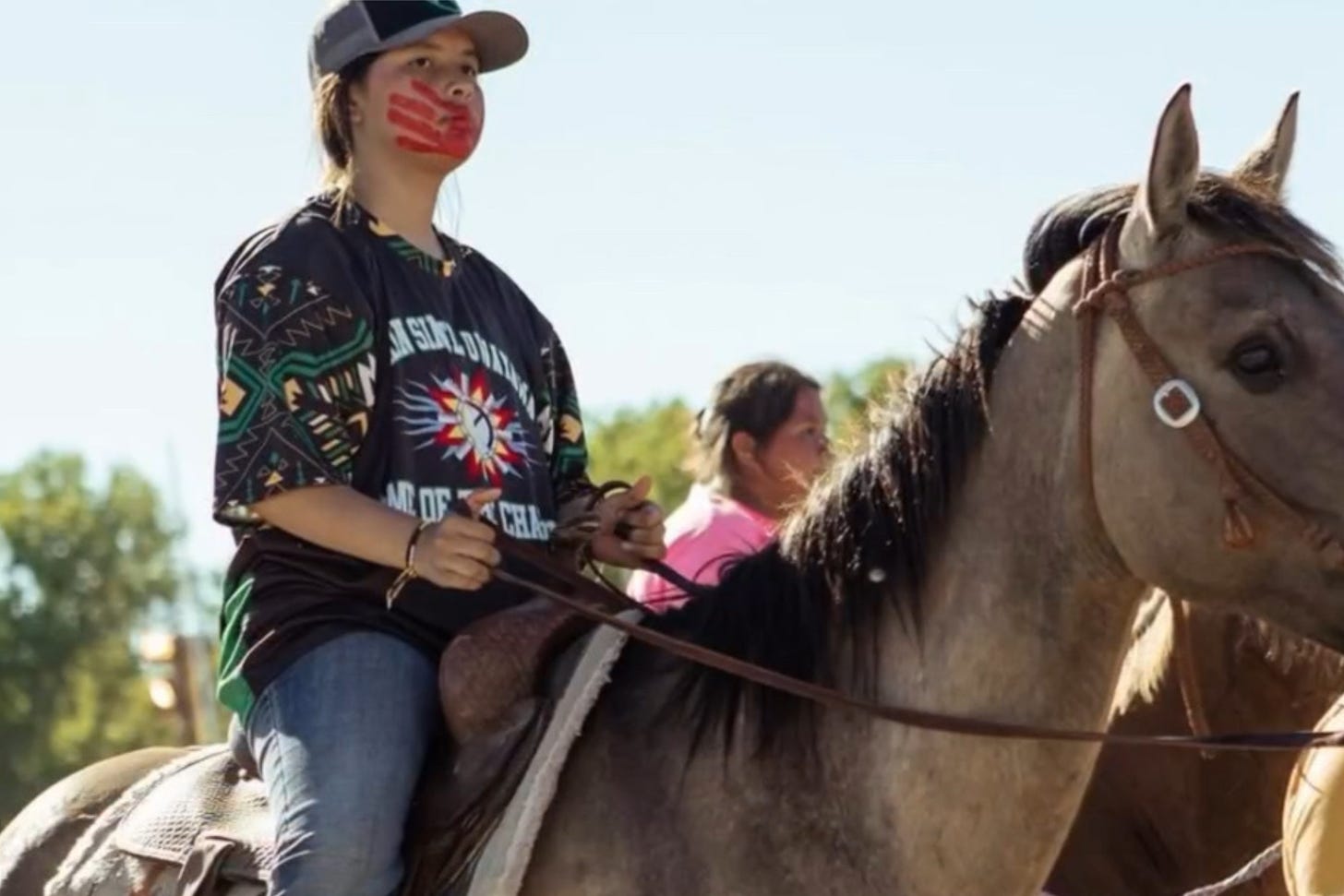 With her MMIP red hand, a young lady rides into town on the Crazy Horse ride.