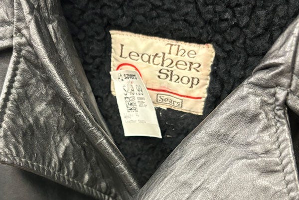 A leather jacket with a vintage "The Leather Shop Sears" tag