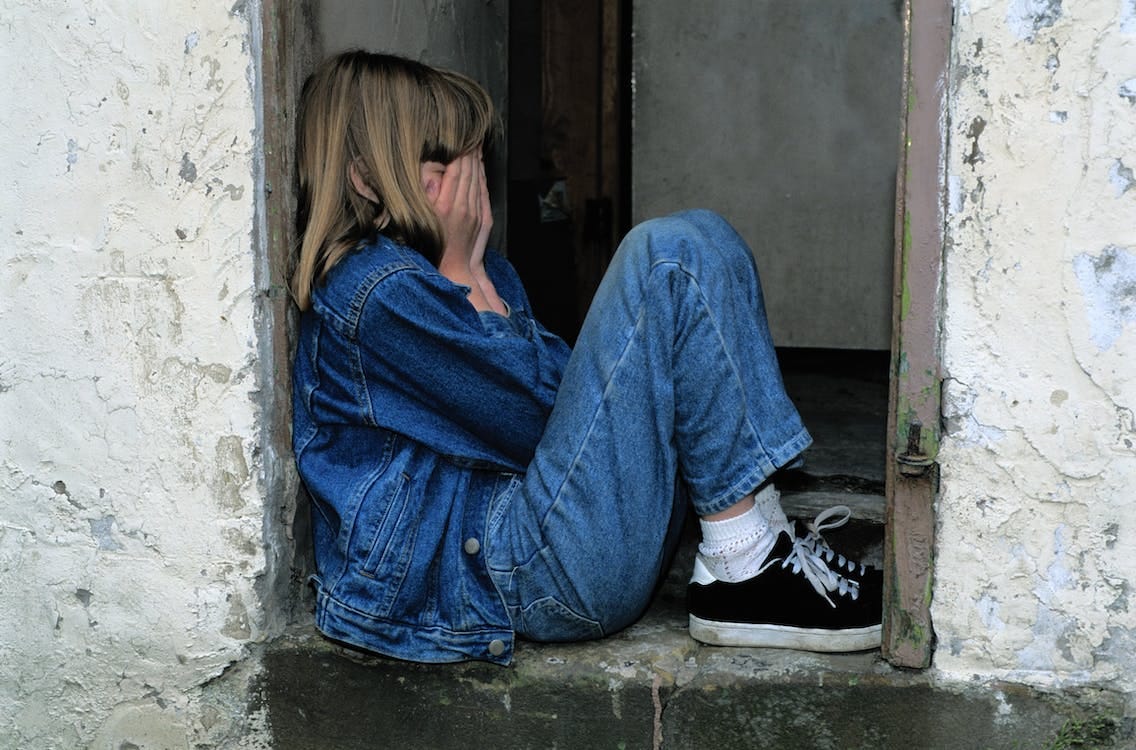 Lonely Girl sitting on a Doorway  Stock Photo