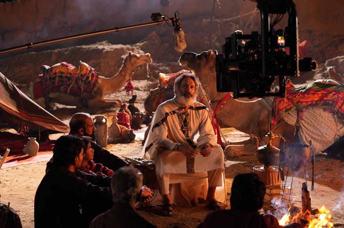 Men sit with camels around a fire, on the set of Daniel, the new film by the Kooman brothers