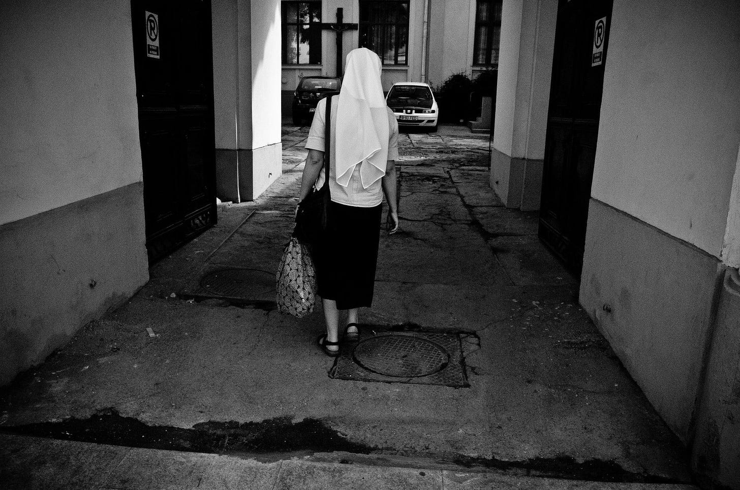 Photo of nun walking through dilapidated alley