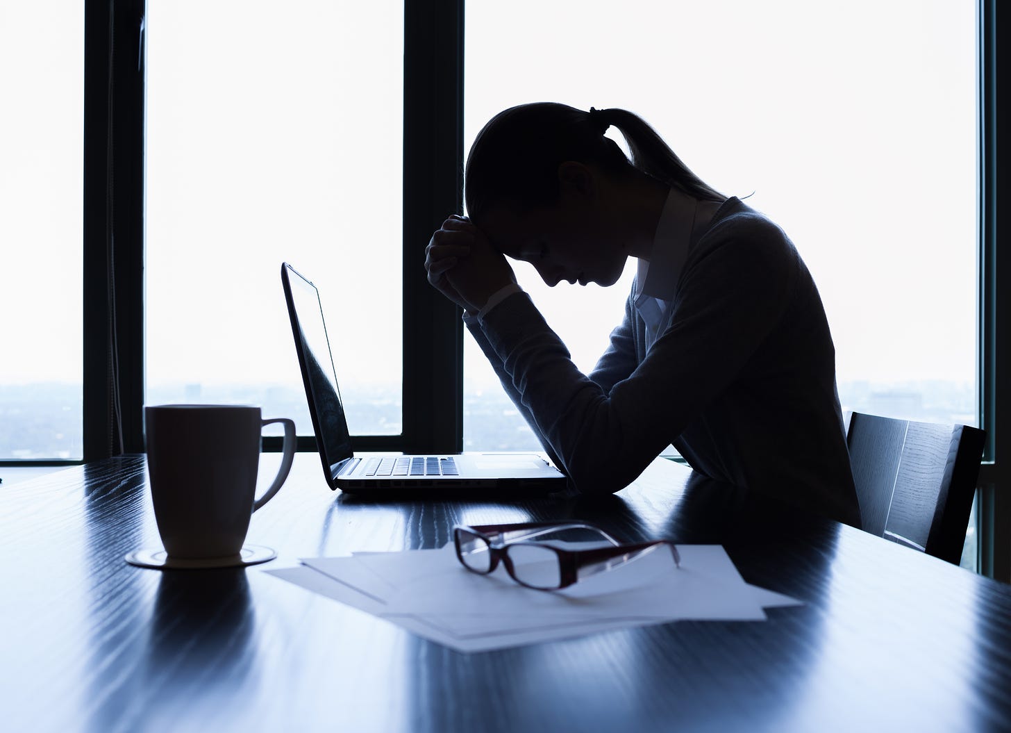 Silhouette of stressed professional woman at her desk.