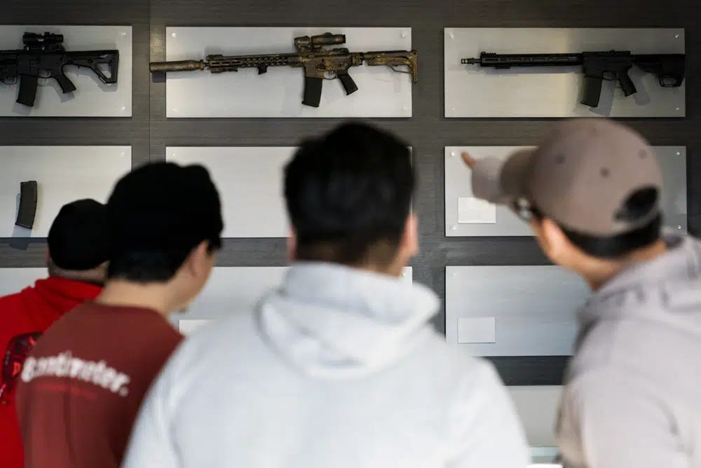 Customers look at AR-15-style rifles on a mostly empty display wall at Rainier Arms Friday, April 14, 2023, in Auburn, Wash. as stock dwindles before potential legislation that would ban future sale of the weapons in the state. House Bill 1240 would ban the future sale, manufacture and import of assault-style semi-automatic weapons to Washington State and would go into immediate effect after being signed by Gov. Jay Inslee. (AP Photo/Lindsey Wasson)