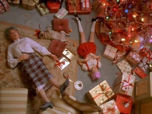 This may contain: a man laying on top of a couch next to a christmas tree filled with presents