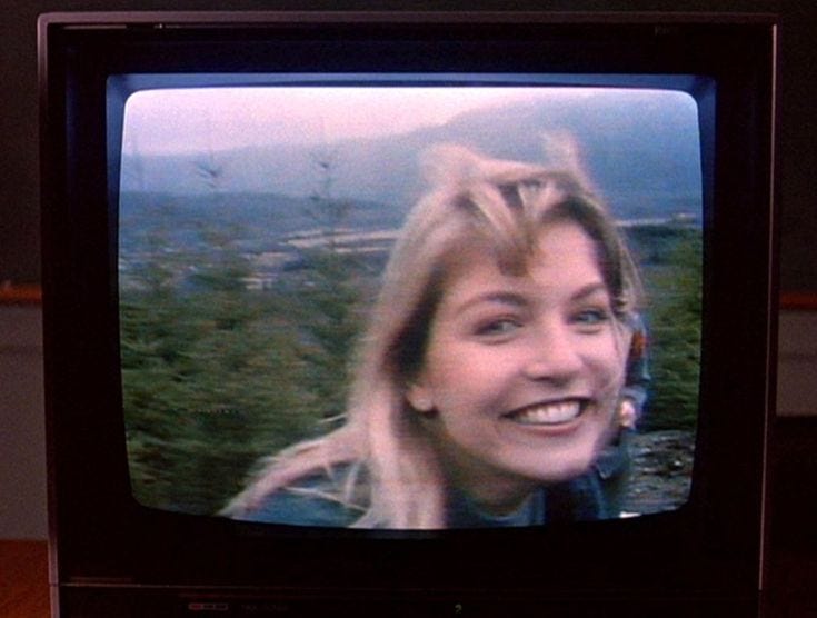This may contain: a woman is smiling while looking at the camera on an old television set in front of her