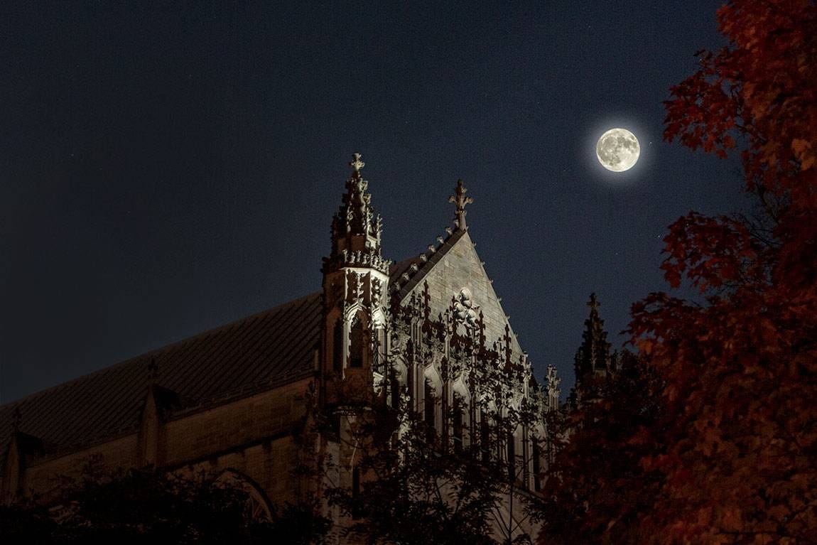 Moon over gothic college building.