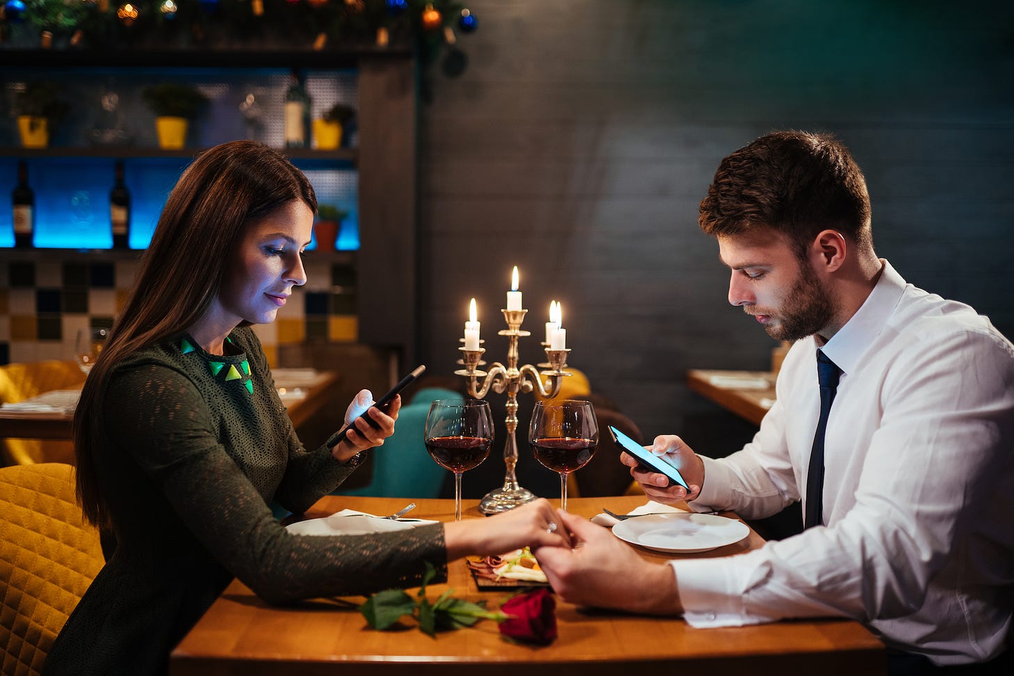 Image of couple looking at phones while dining