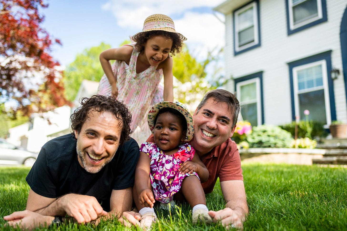 family with children sitting on green lawn