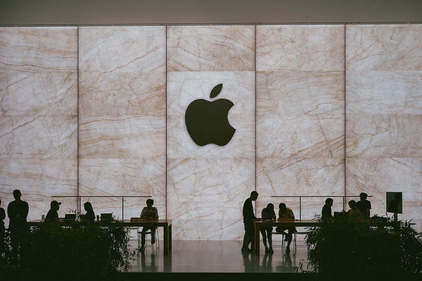 The silhouette of customers and the Apple logo on the upper level of Apple Cotai Strip.