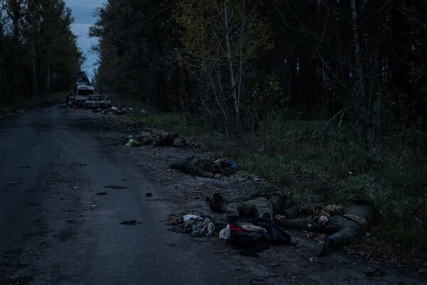 Multiple bodies lying along a dirt road.