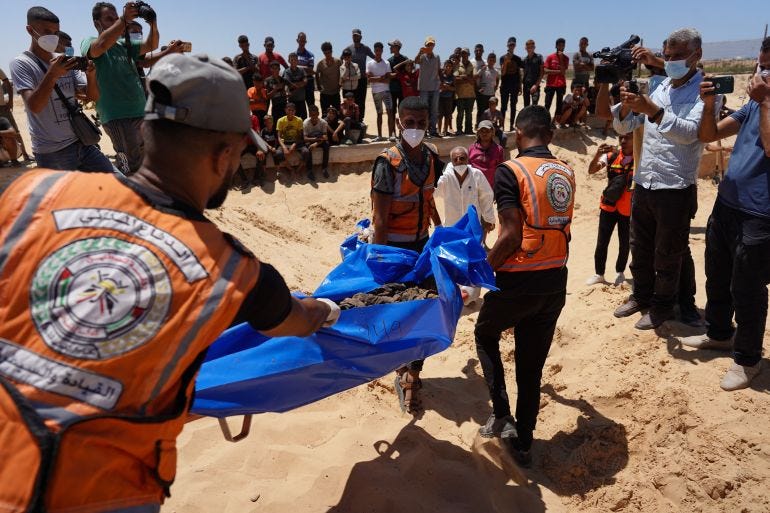 People watch as bodies that were taken and later released by Israel are buried during a mass funeral at a cemetery in Khan Yunis in the southern Gaza Strip on August 5, 2024, amid the ongoing conflict between Israel and the Palestinian Hamas militant group. (Photo by Bashar TALEB / AFP)