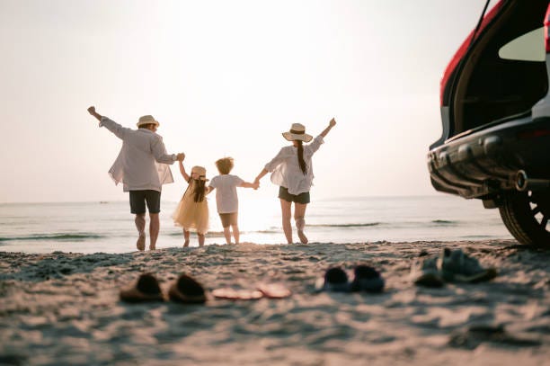 Family vacation holiday, Happy family running on the beach in the sunset. Back view of a happy family on a tropical beach and a car on the side. Family vacation holiday, Happy family running on the beach in the sunset. Back view of a happy family on a tropical beach and a car on the side. Journey of Parenthood stock pictures, royalty-free photos & images
