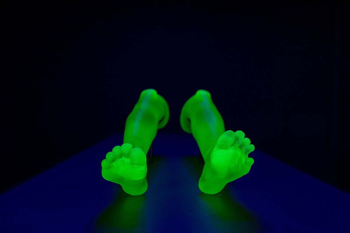 Pair of green glass disembodied women's legs against black background