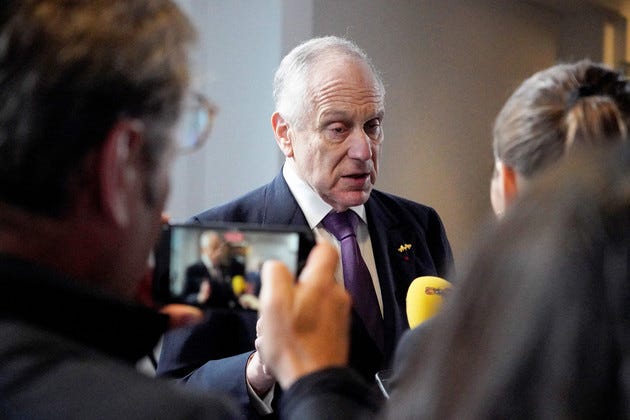 Ronald Lauder speaks to press recording him on a cellphone and holding up a microphone.
