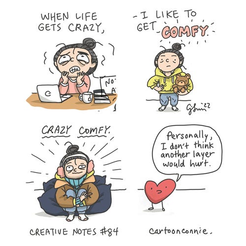 Crazy Comfy (Creative Notes #84) 4-panel comic comic by Connie Sun from Creative Notes webcomic series episode 84. Cartoon of a girl with a bun, sitting at a desk, feeling anxious and overwhelmed in panel 1. In panel 2, she is calmer and standing akimbo in very comfy attire, holding a teddy bear. Caption reads, “When life gets crazy, I like to get COMFY,” the word comfy written in pink bubble script. In panel 3, she is wearing an unreasonable amount of cozy mismatched clothing, sitting on a pile of pillows. In panel 4, an oversized cartoon heart says, "Personally, I don't think another layer would hurt." Full comic with bonus panel on Tinyview app. Link to webcomic series tinyview.com/connie by Connie Sun, cartoonconnie, 2022.