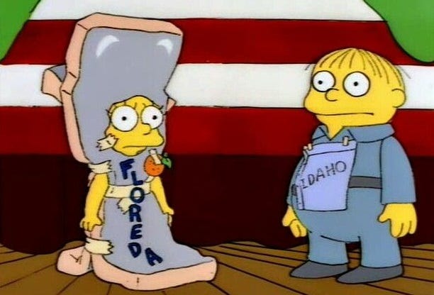 Simpsons screenshot showing Ralph Wiggum in his "I'm Idaho!" costume (a piece of paper reading "Idaho" pinned to his shirt)