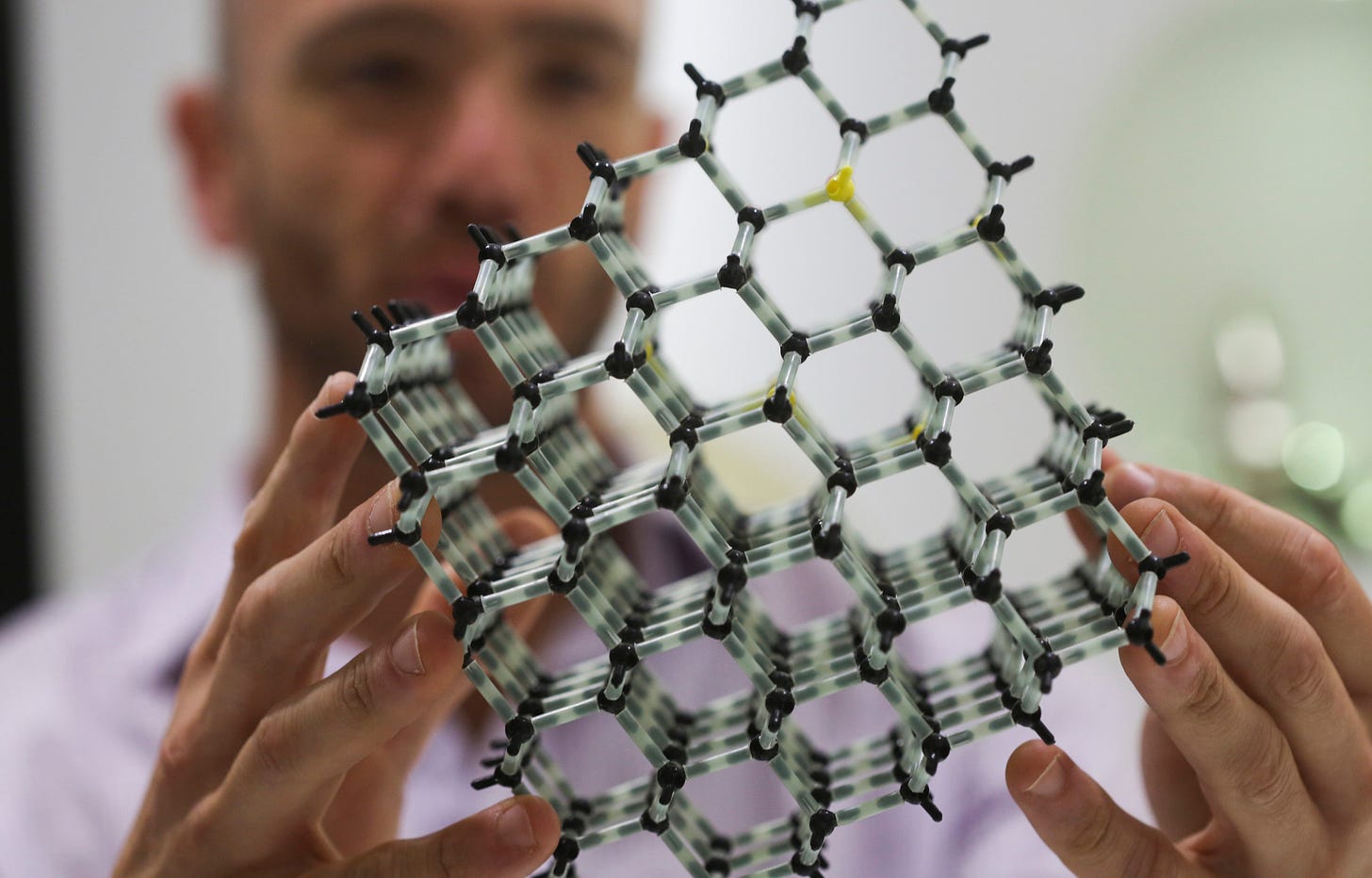 An employee at Element Six holds a molecular structure model of a diamond.Photographer: Chris Ratcliffe/Bloomberg