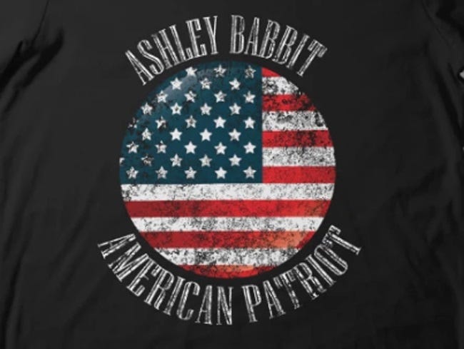 image of  T-shirt design featuring a faded, faux-'distressed' US flag and misspelled slogan, 'Ashley Babbit American Patriot' 