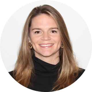 A headshot of a smiling woman with long brown hair wearing a black turtleneck sweater against a white background.