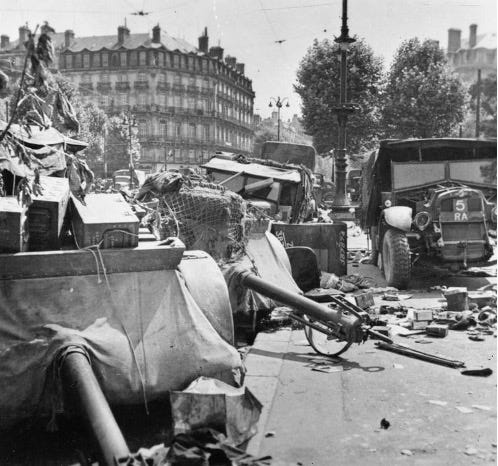 Black and white photo of World War II combat in France, June 1940. The photo shows several British Army artillery limbers and vehicles abandoned in a French town. British forces are retreating from France to the beaches of Dunkirk for evacuation with the advance of the German Army.