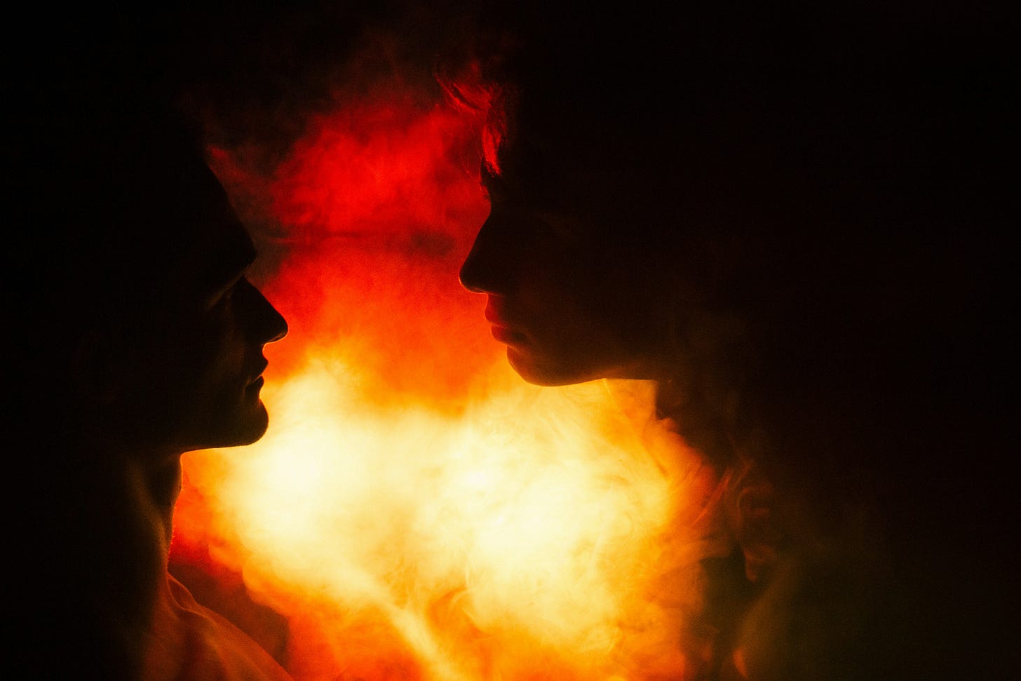 couple staring at each other in front of a fire
