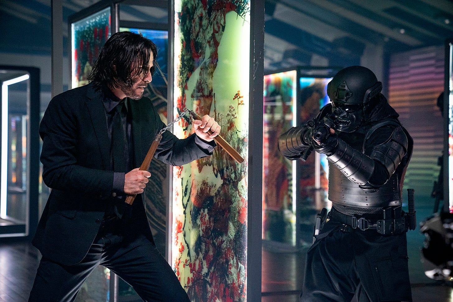 Keanu Reeves, as John Wick, holds nunchucks as he prepares to face off with an armored goon.