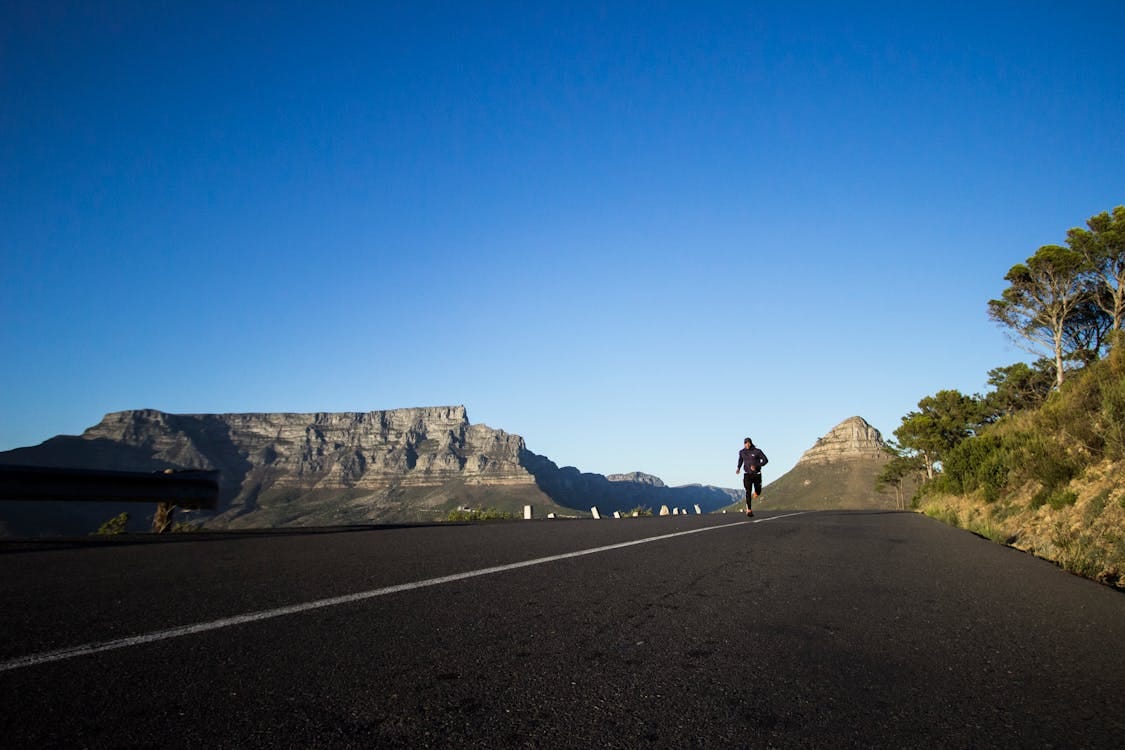 Free Man jogging along a scenic road with Table Mountain view in Cape Town. Stock Photo