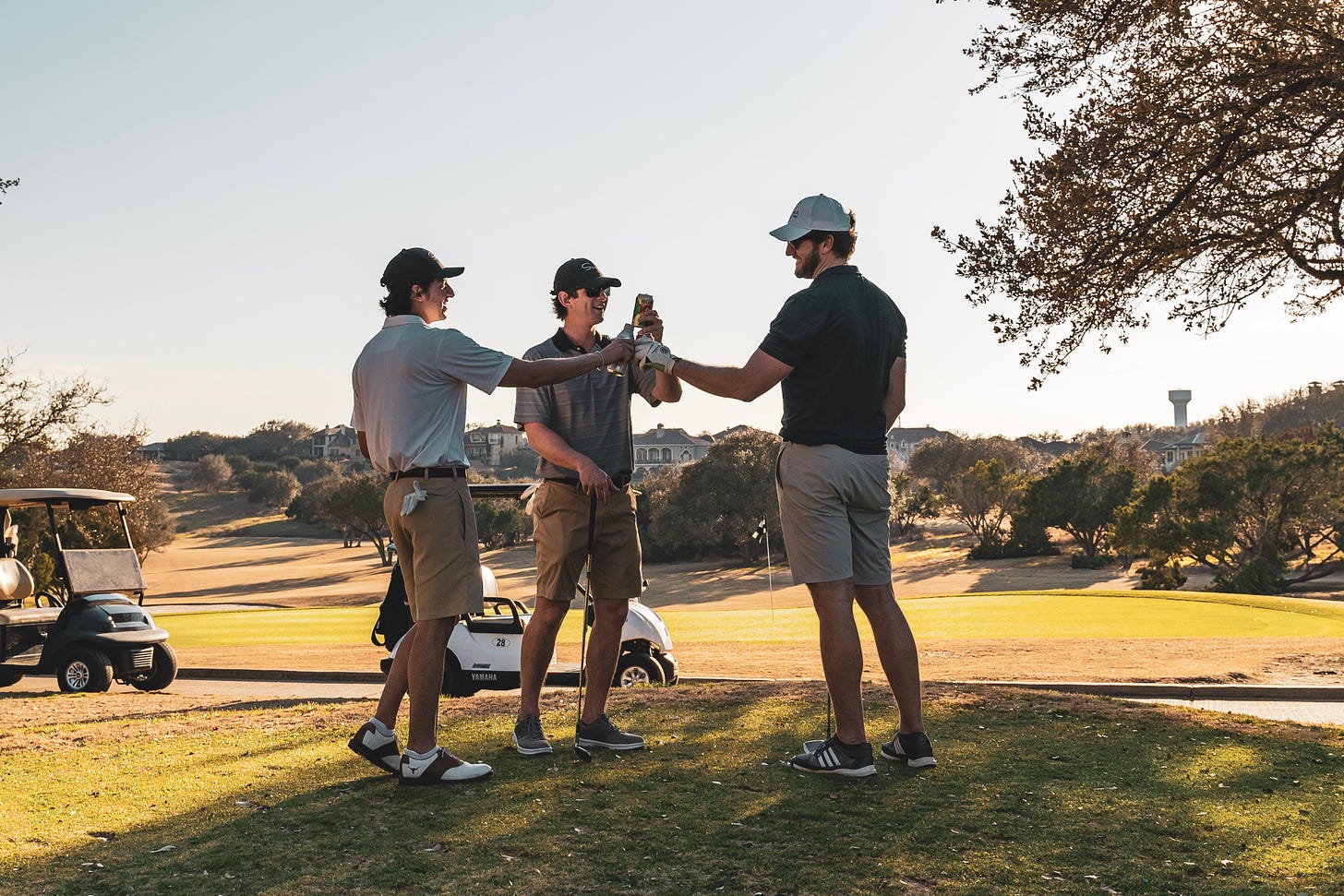 Three men, all appear to be white, enjoying a can of beer after a round of golf. Maybe they also made a deal, it's hard to say.