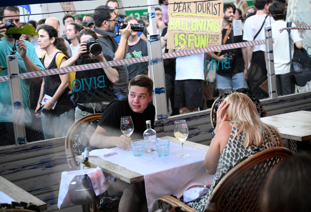 Two diners shrinking away from protesters as they sit across from each other at a restaurant table.