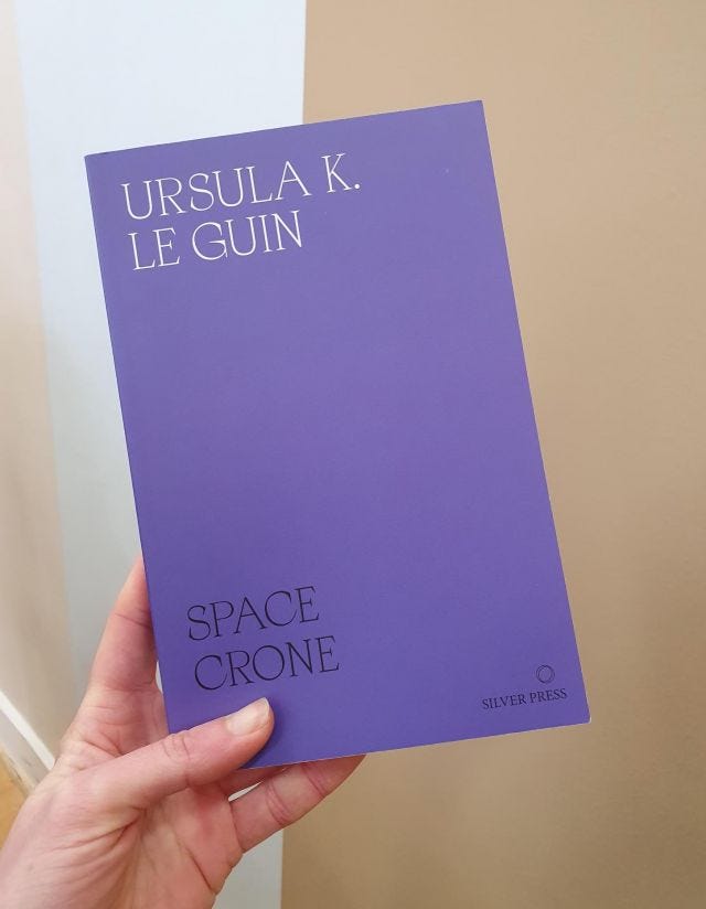 my hand holding a copy of Space Crone, a collection of Ursula le Guin's writing on feminism and gender 