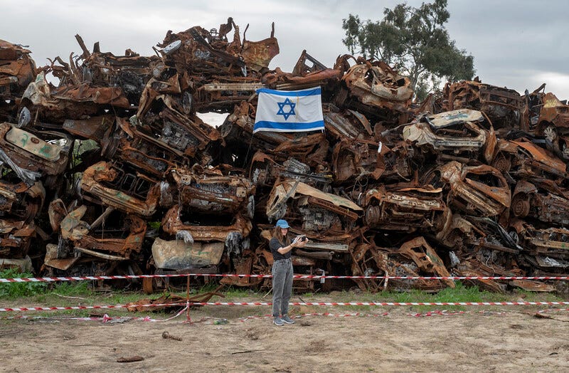 Israeli soldiers view stacks of burnt cars in Netivot