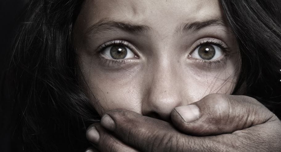 A young girl with a frightened expression, her mouth covered by a hand, symbolizing the growing threat of human trafficking.