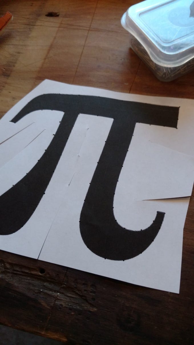 A pi symbol printed on paper with tiny dots outlining it.