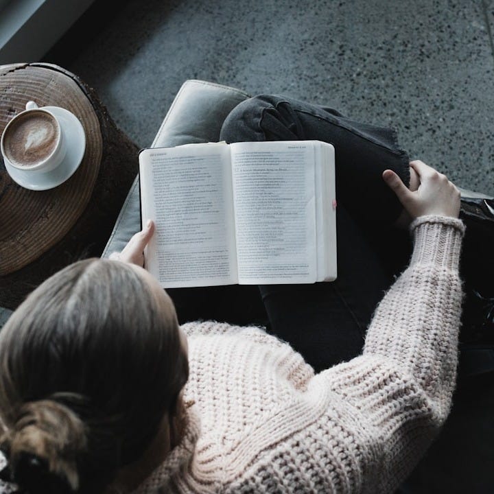 woman in white sweater reading book