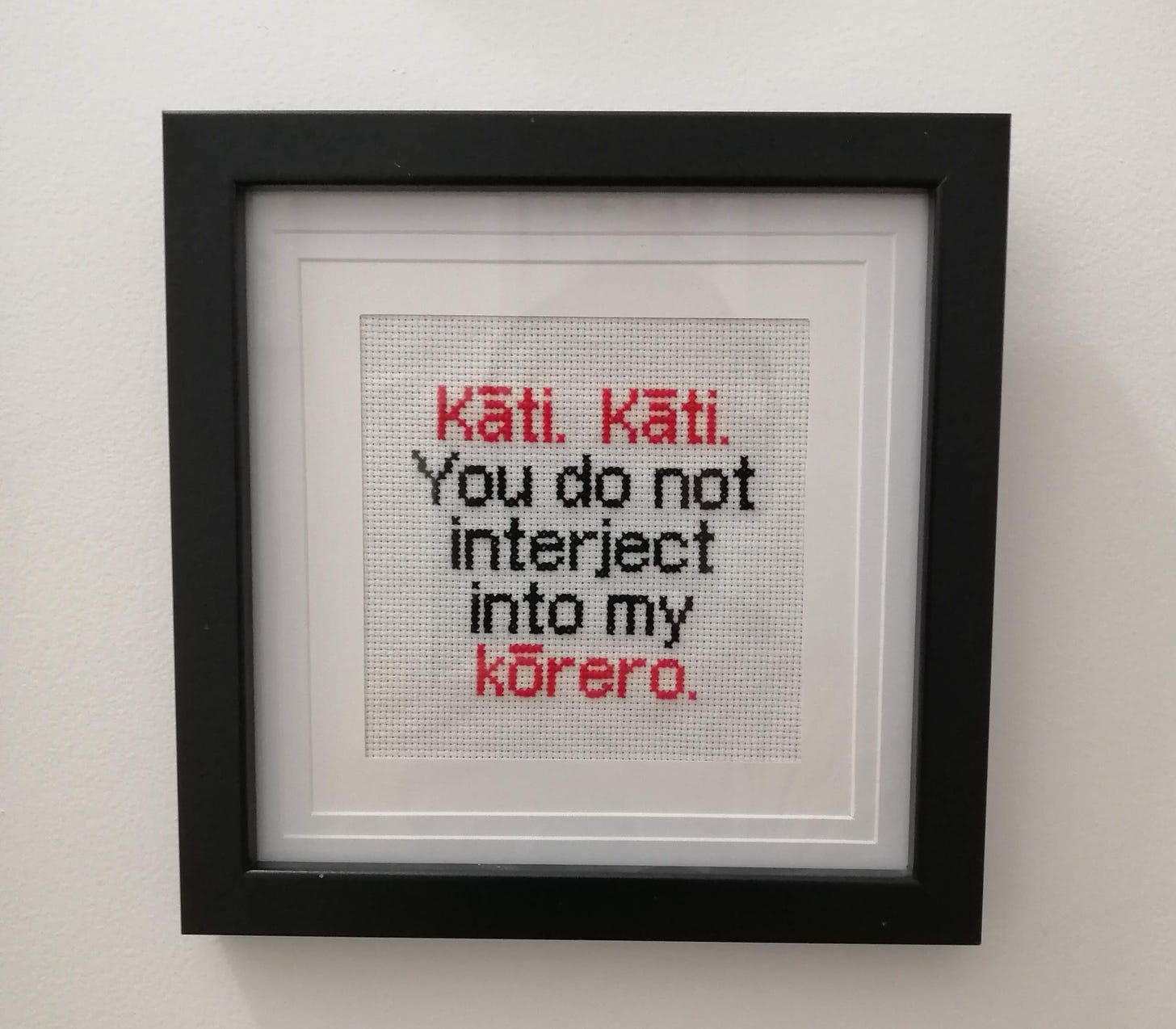 Cross stitch in a frame with text that says "kāti. Kāti. You do not interject into my kōrero"