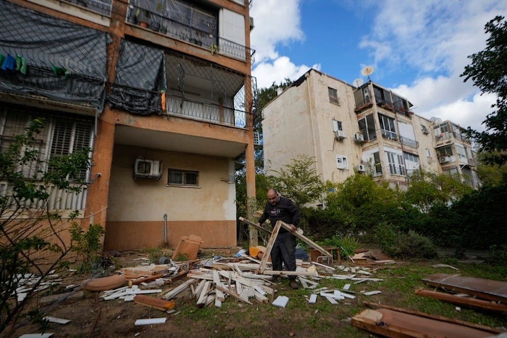 A man works next to a damaged building near the site where a missile launched from Yemen landed in Yafa district, in Tel Aviv, occupied Palestine, Tuesday, Dec. 31, 2024 (AP)