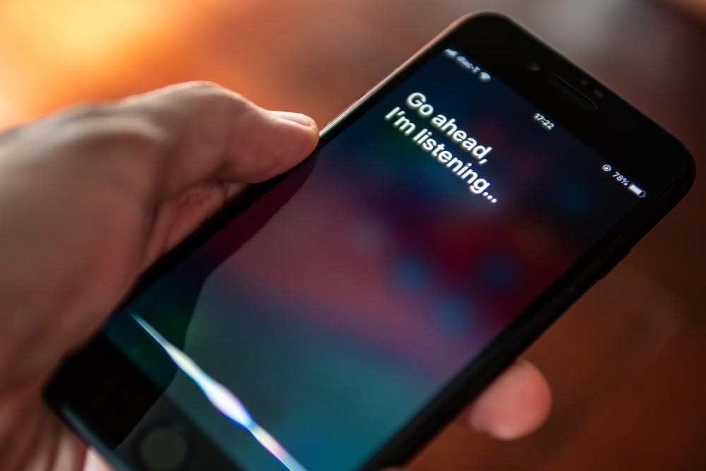 A hand holding an iphone with the words "Go ahead...I'm listening" written on the screen.