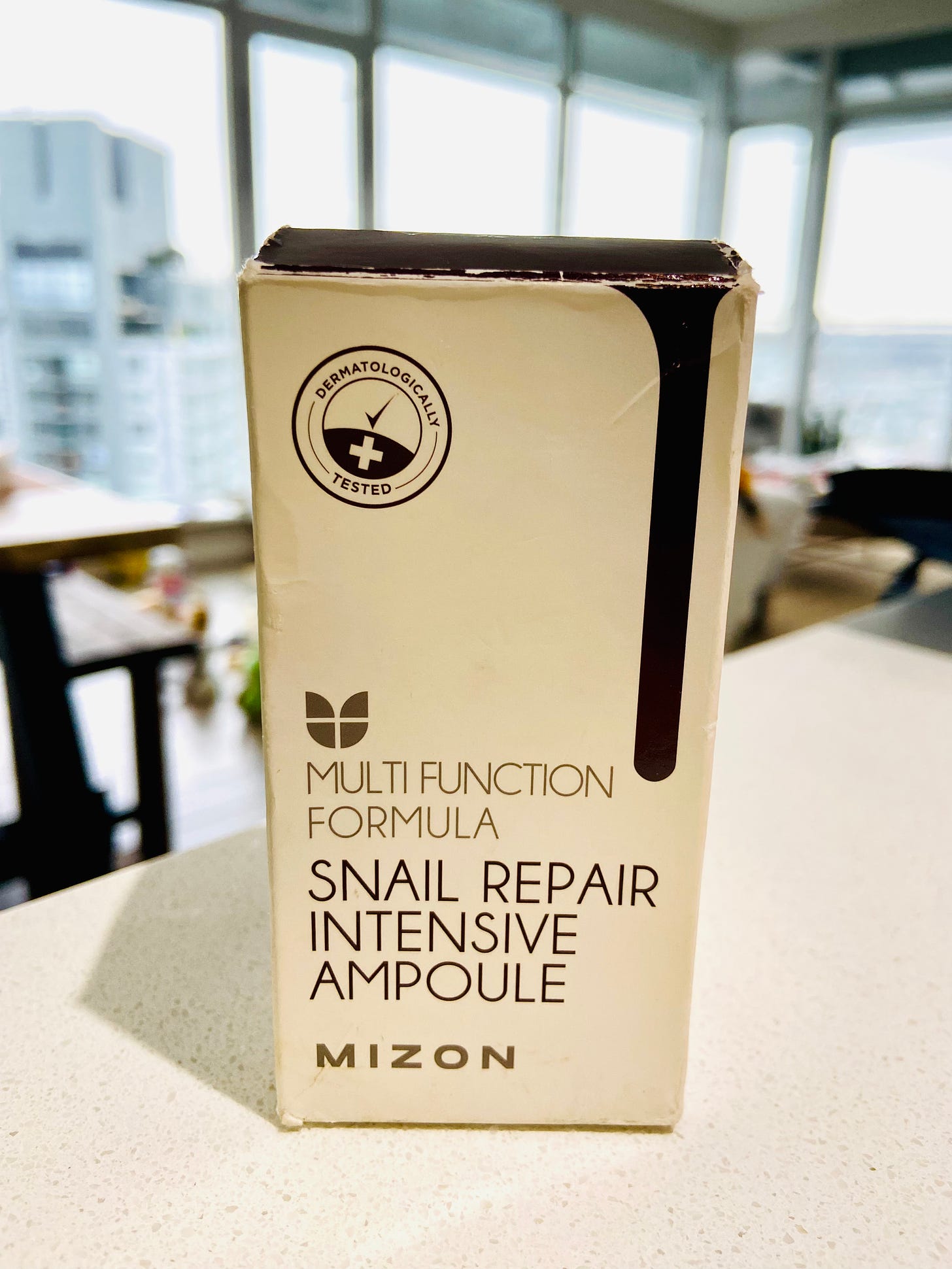 Cardboard box holding Mizon serum bottle.