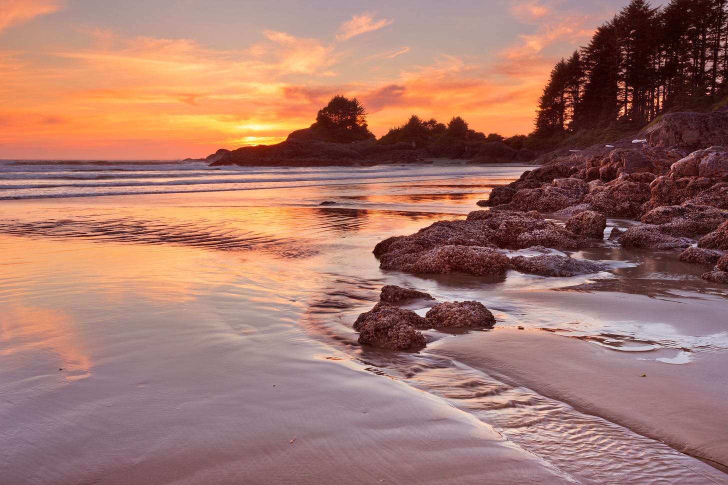 Beautiful sandy beach and rocks with brilliant orange sky at sunset - this was a beach near Tofino