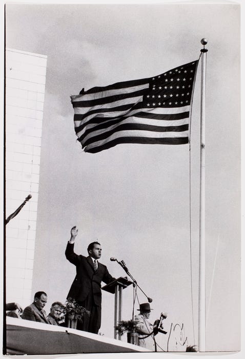 Richard M. Nixon making a campaign speech at shopping center beneath an American  flag ] | International Center of Photography