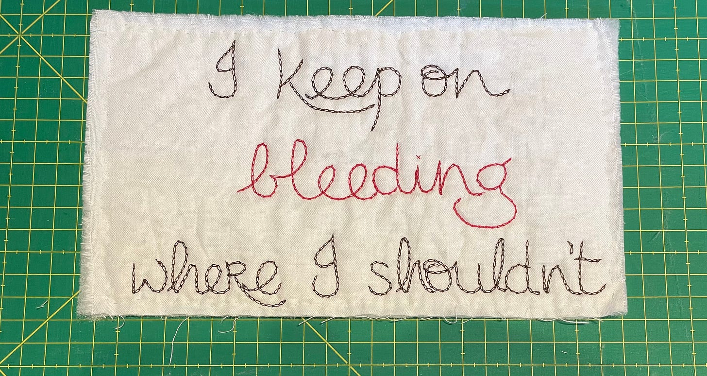 A small quilted piece that reads “I keep on bleeding where I shouldn’t”.
