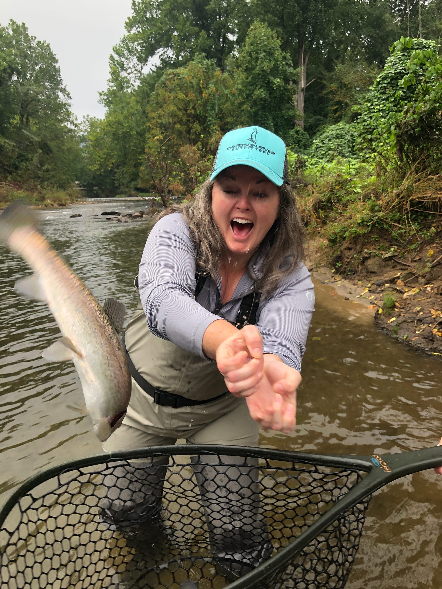 a woman fly fishing, losing her grip on the fish