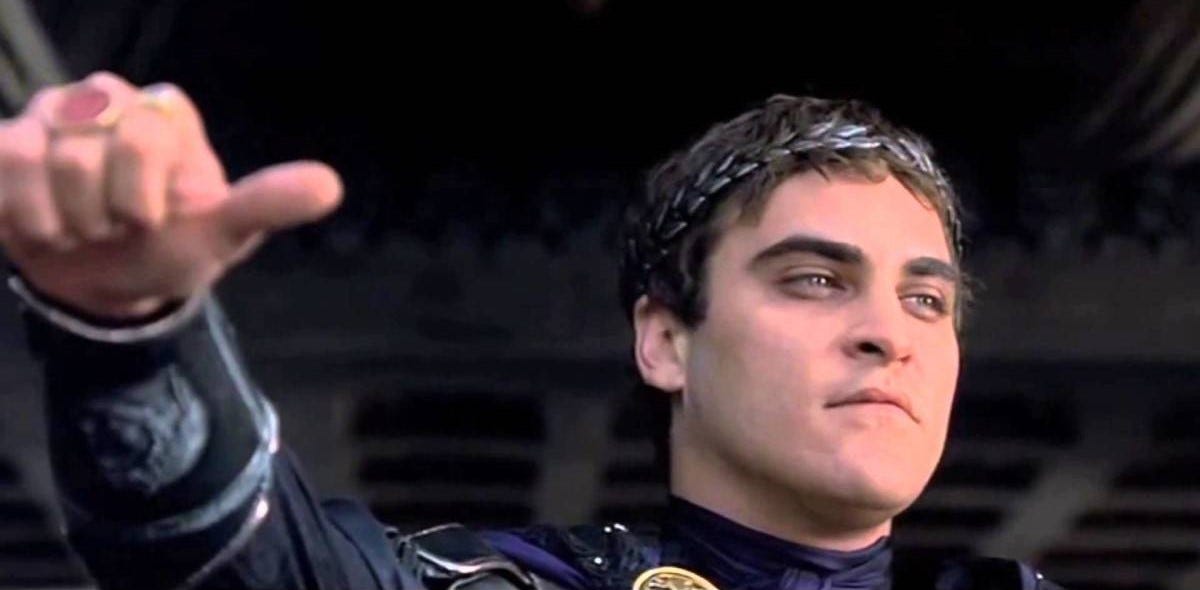 Joaquin Phoenix in the movie Gladiator. He is holding his thumb out, prepared to give a thumbs up or down to see if a gladiator should live. 