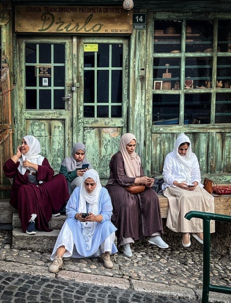 Photograph of five women on their phones outside a shop