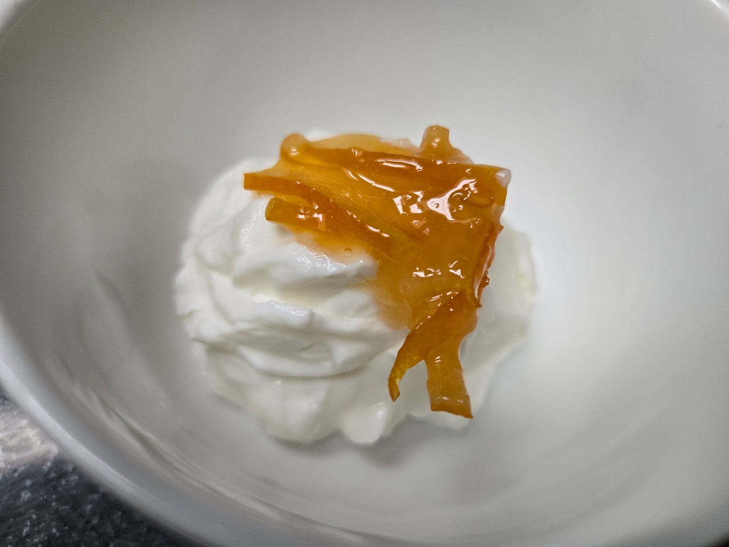 A small pile of Greek yogurt with meyer lemon marmalade in a white bowl.